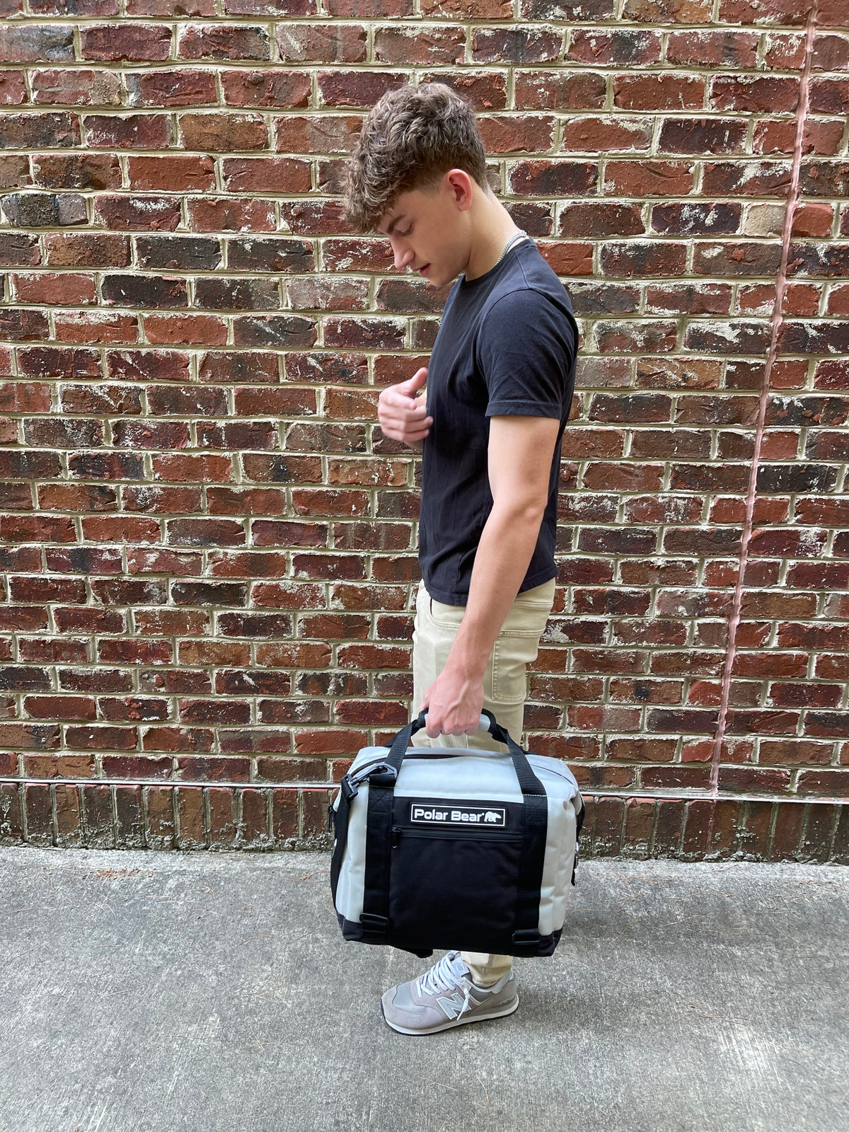 Small nylon cooler bag with crossbody strap carried by a person