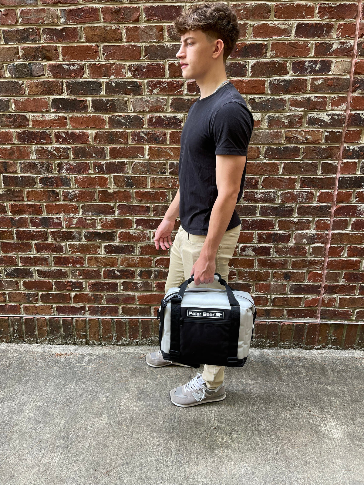 Dark nylon soft cooler bag with Polar Bear logo, front zip pocket, and carry strap