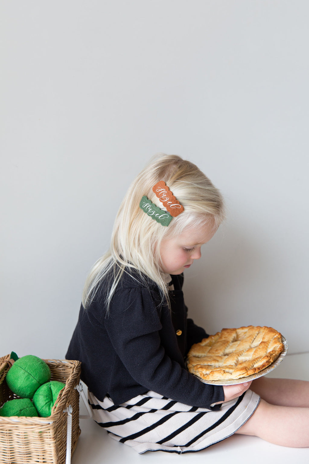 Child wearing felt snap clip with orange script name Hazel and green accent