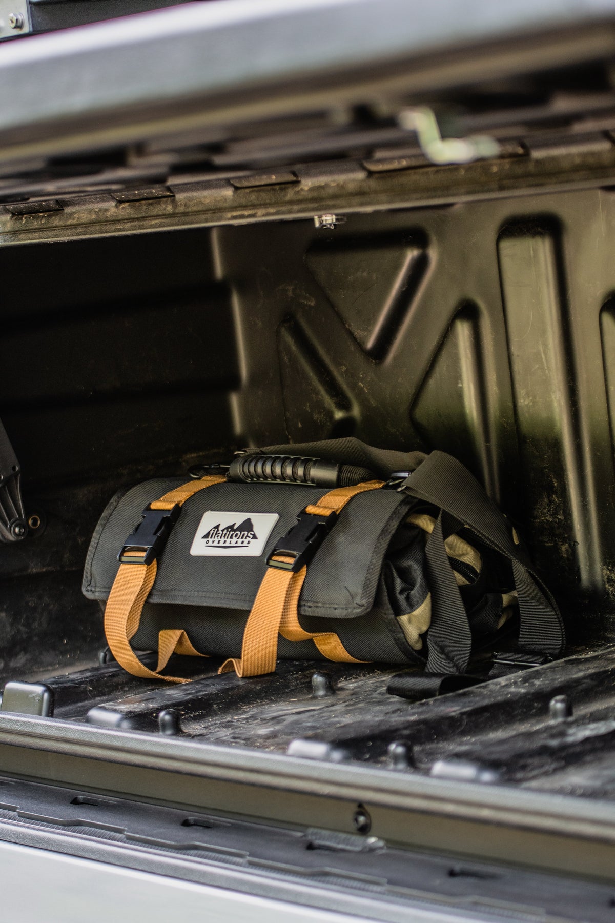 RiPouch™ Gear Roll dark fabric pouch organizer with tan straps, shown in vehicle cargo.