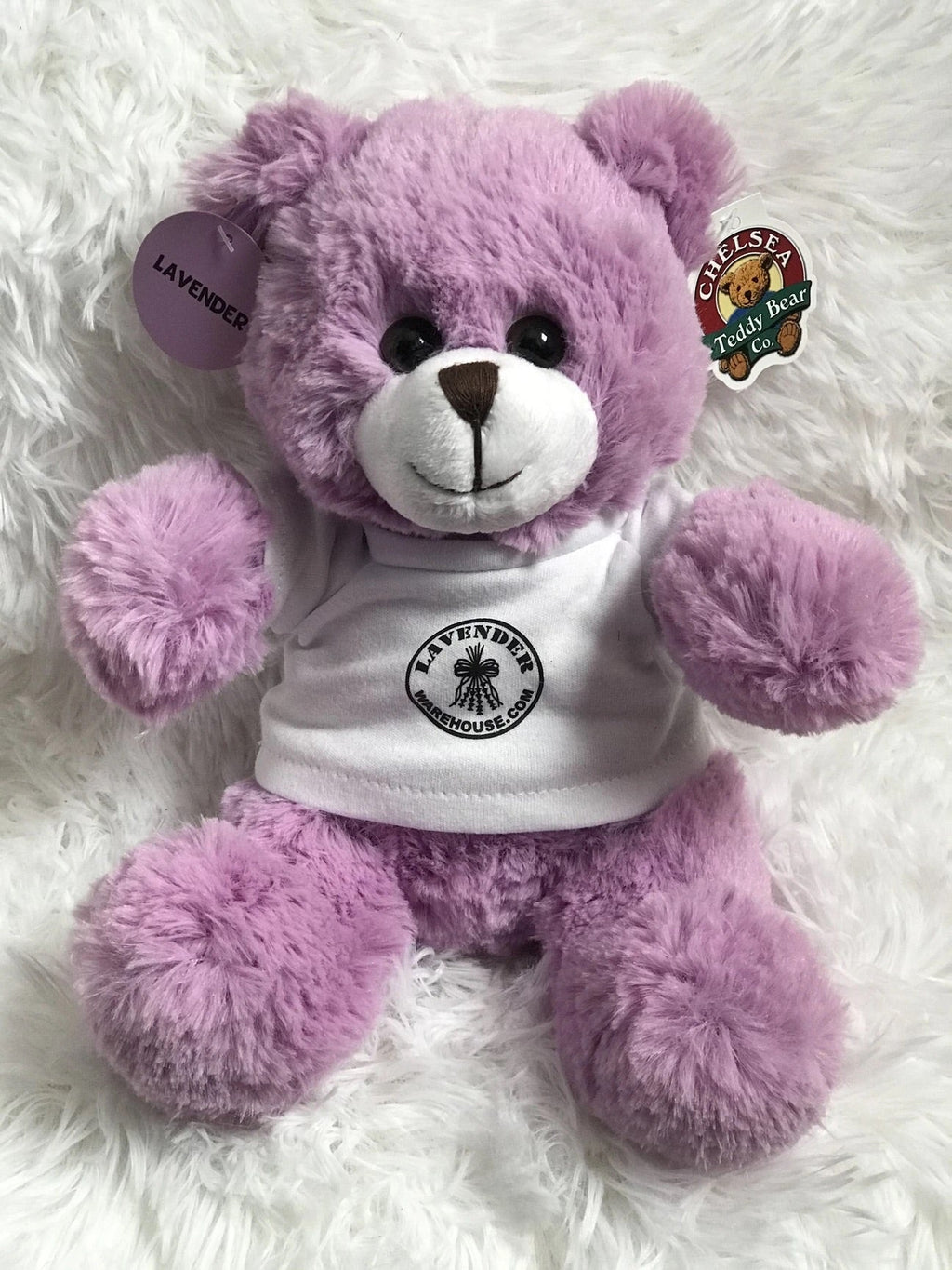 Purple plush teddy bear wearing lavender-themed hoodie with round logo patch