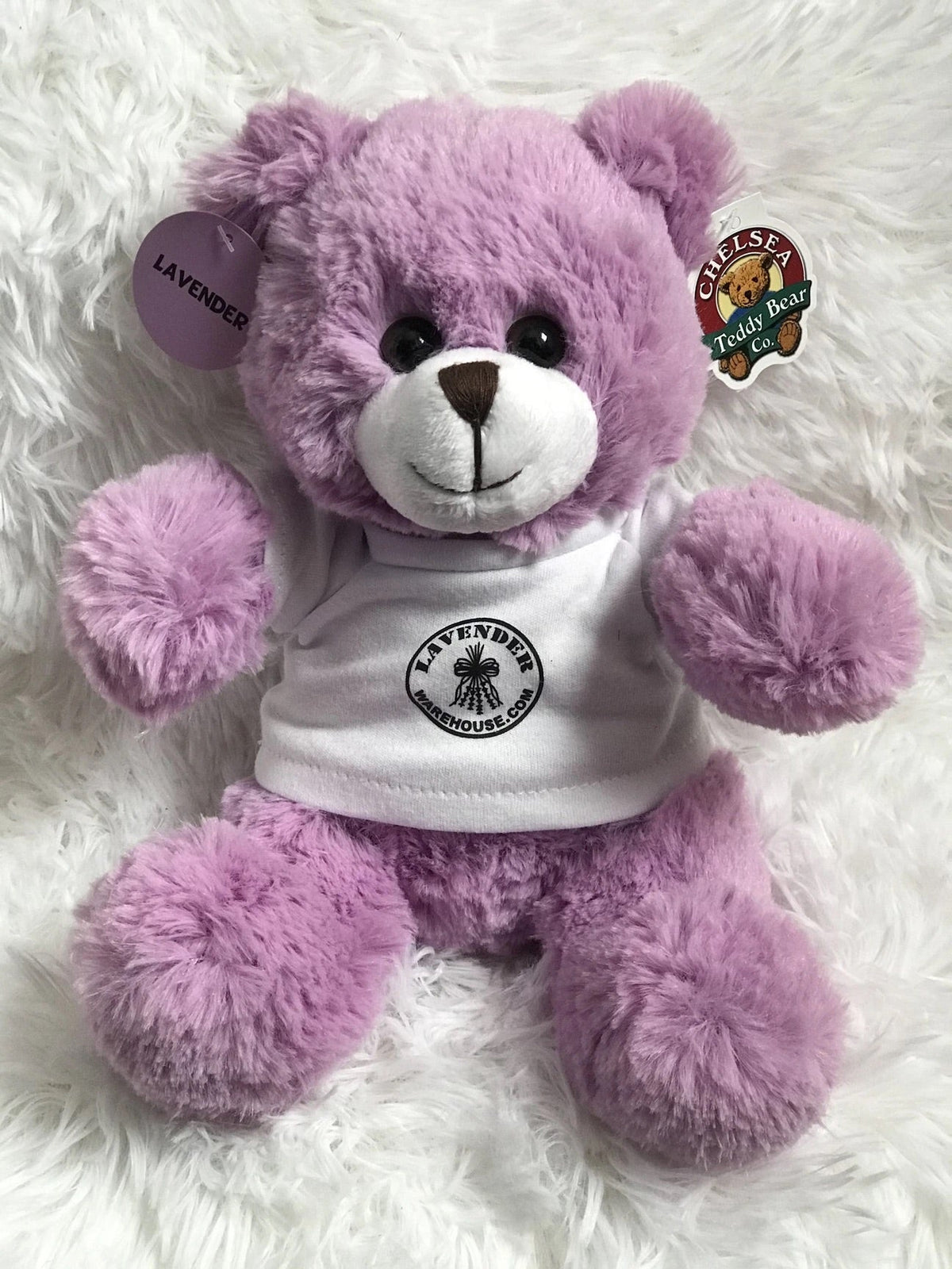 Purple plush teddy bear wearing lavender-themed hoodie with round logo patch