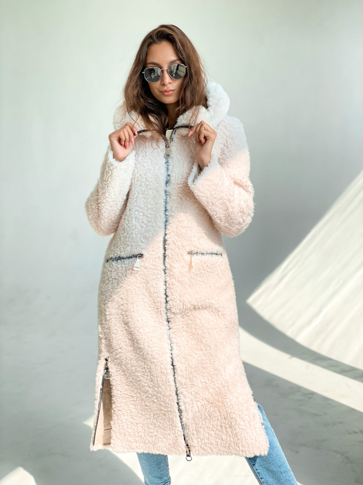 Light blush hooded fur coat with long sleeves, zip front, and side slits