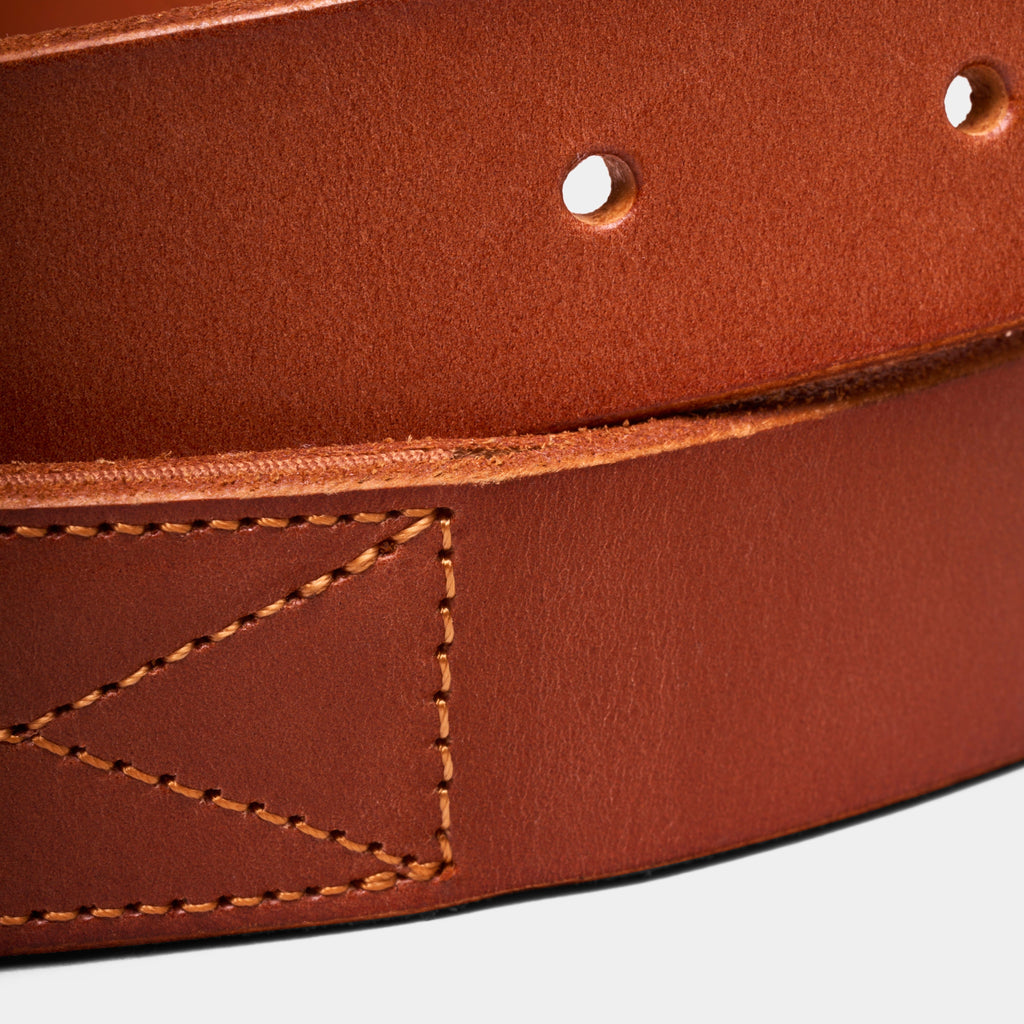 Brown leather belt close-up showing textured grain, edge stitching, and eyelets