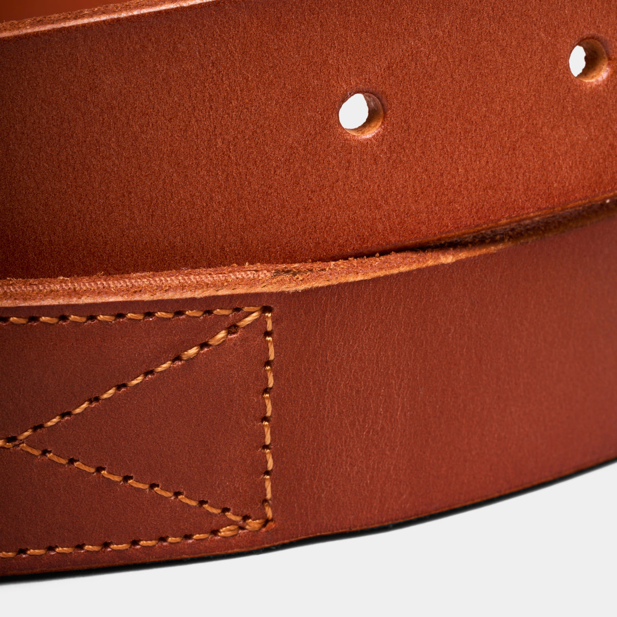 Brown leather belt close-up showing textured grain, edge stitching, and eyelets