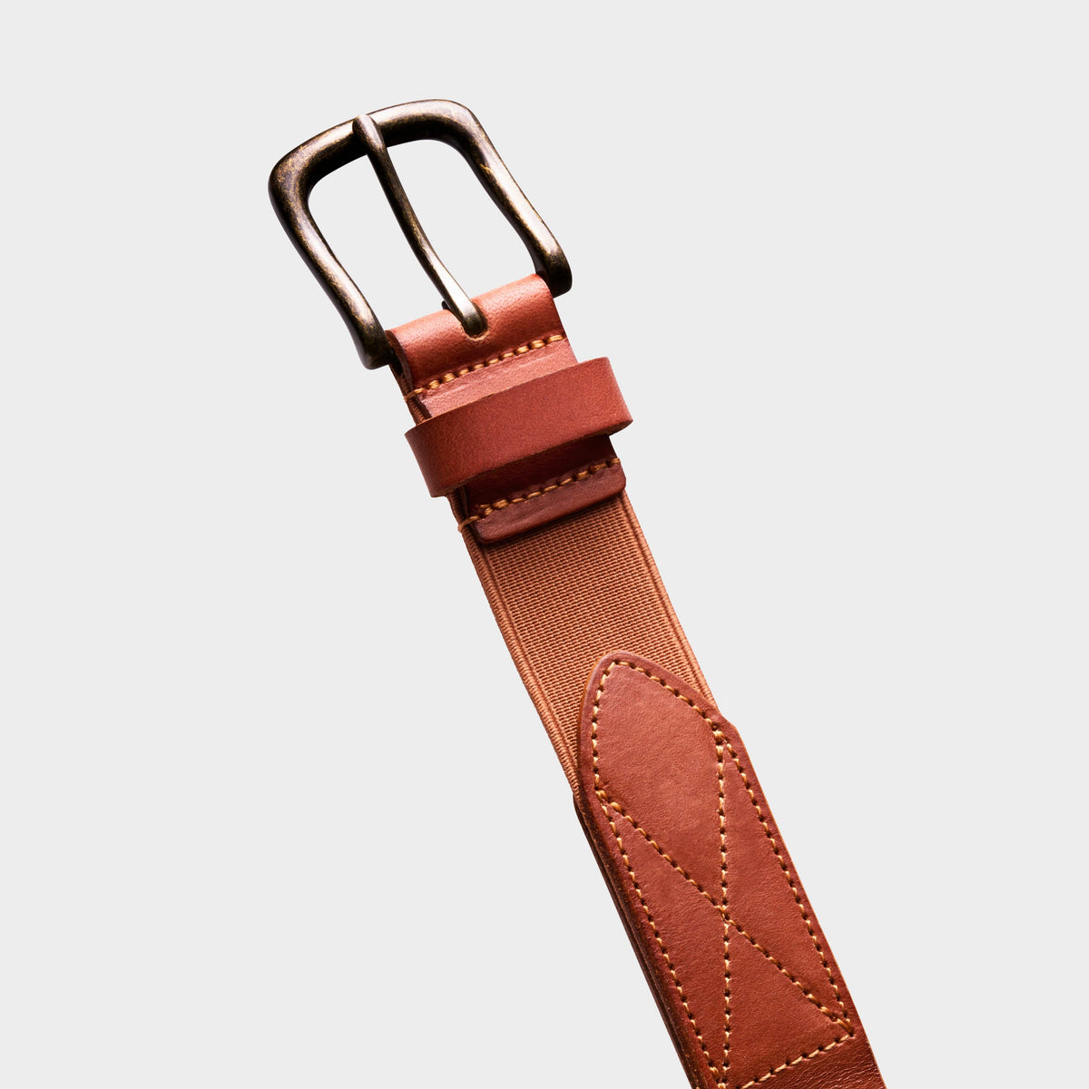 Brown leather stretch belt close-up with metal buckle and stitched tab