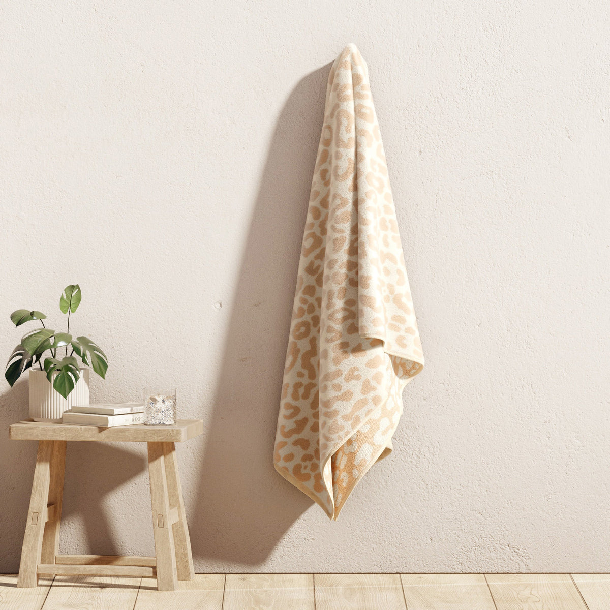 Beige leopard-print cotton velour beach towel hanging against a wall