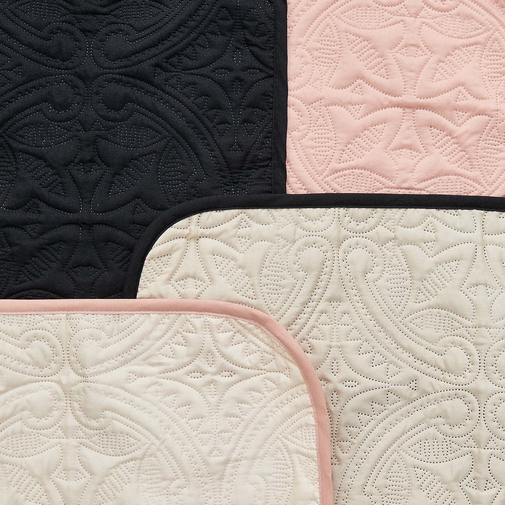 Quilted sofa protector close-up with black and ivory sections and blush pink trim