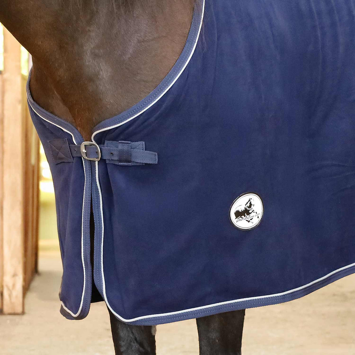 Navy fleece horse cooler blanket close-up, front tie strap, white piping, logo badge