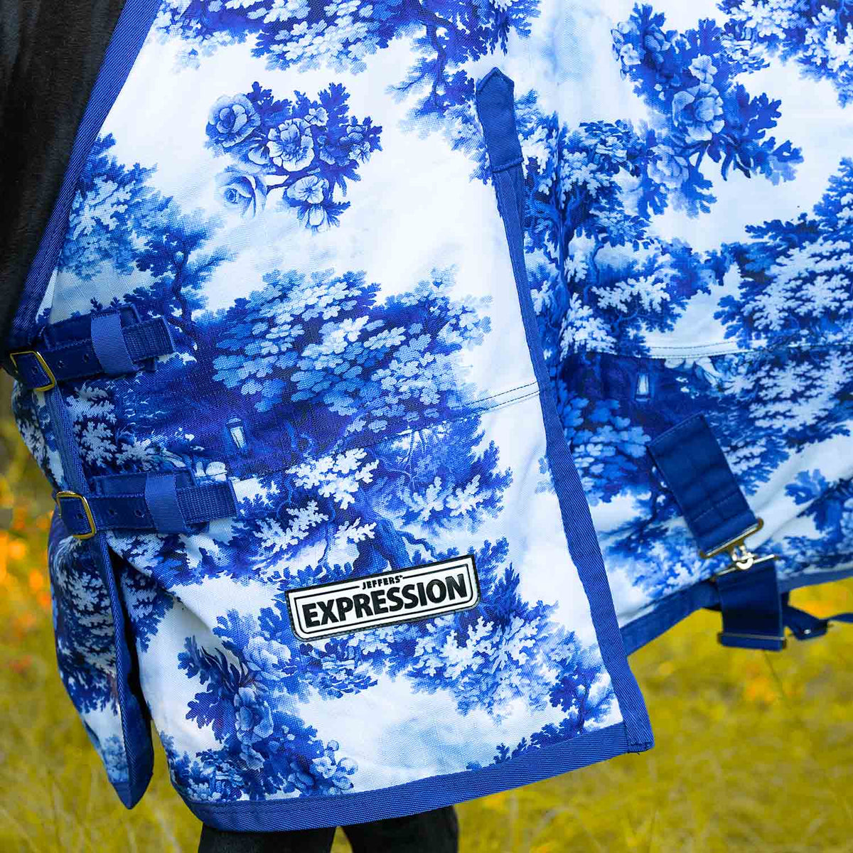 Horse turnout blanket detail in blue floral-tree print with Expression logo and straps