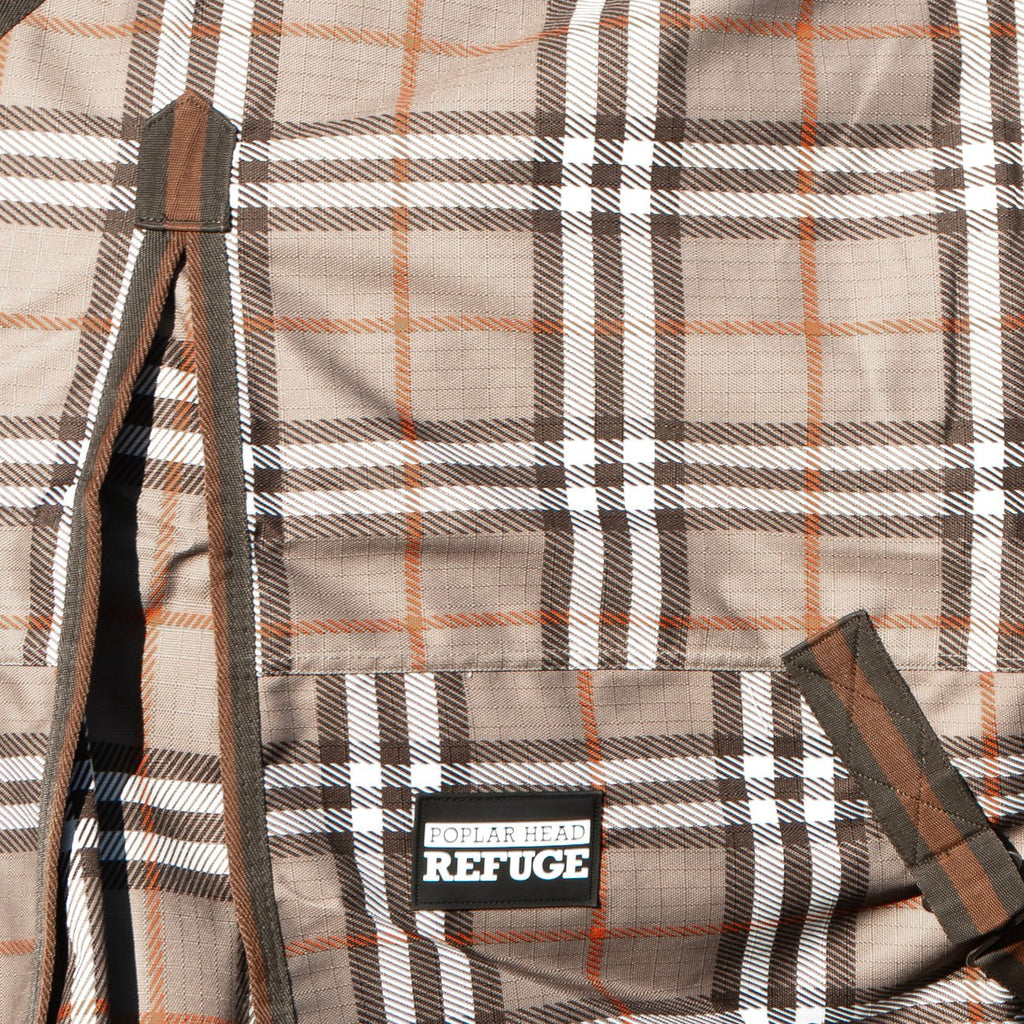 Brand patch on plaid turnout horse blanket with dark trim and side straps