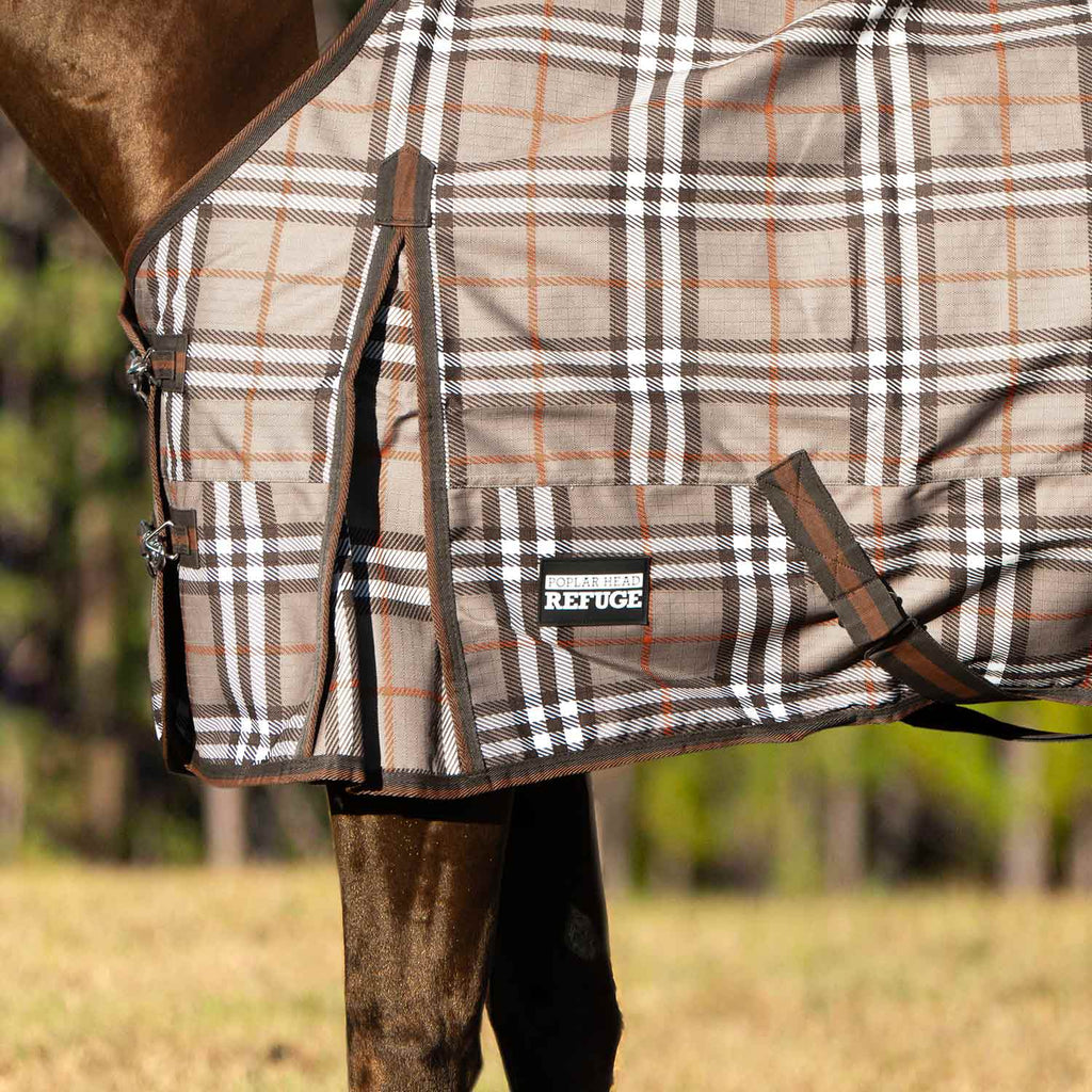 Plaid turnout horse blanket close-up with front straps and brand patch