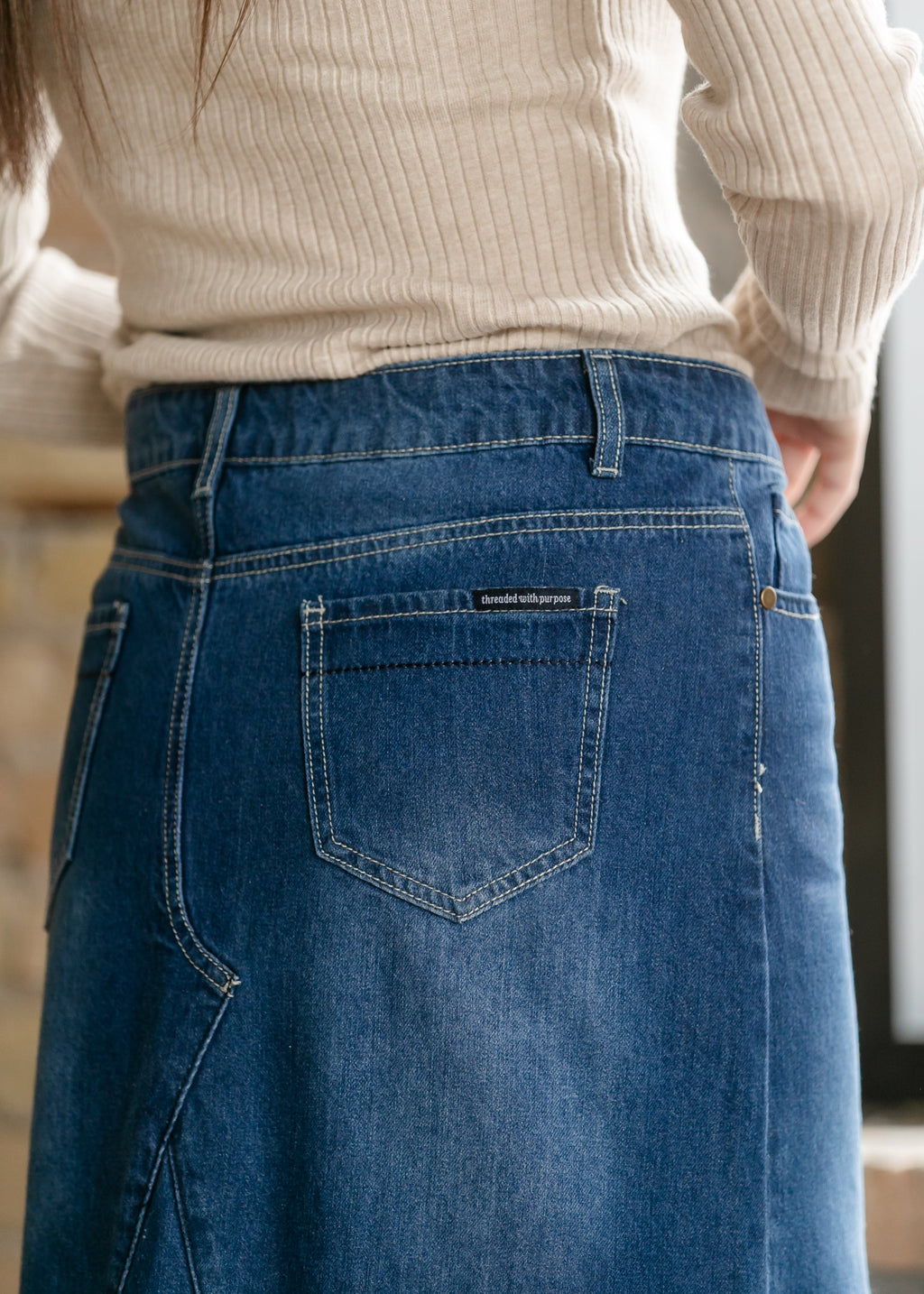 Close-up of dark blue denim skirt with stitched patch pocket and waistband