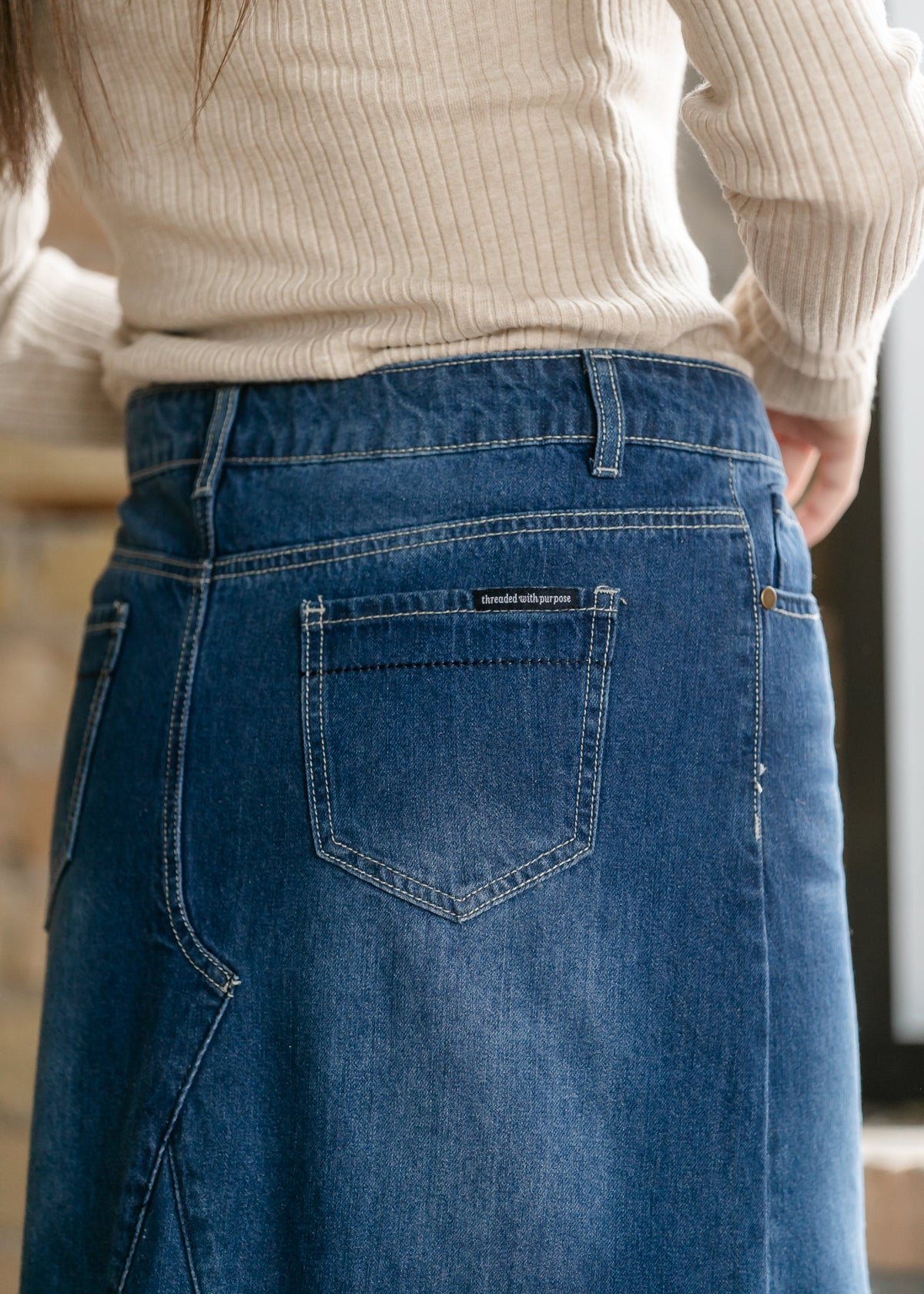 Close-up of dark blue denim skirt with stitched patch pocket and waistband