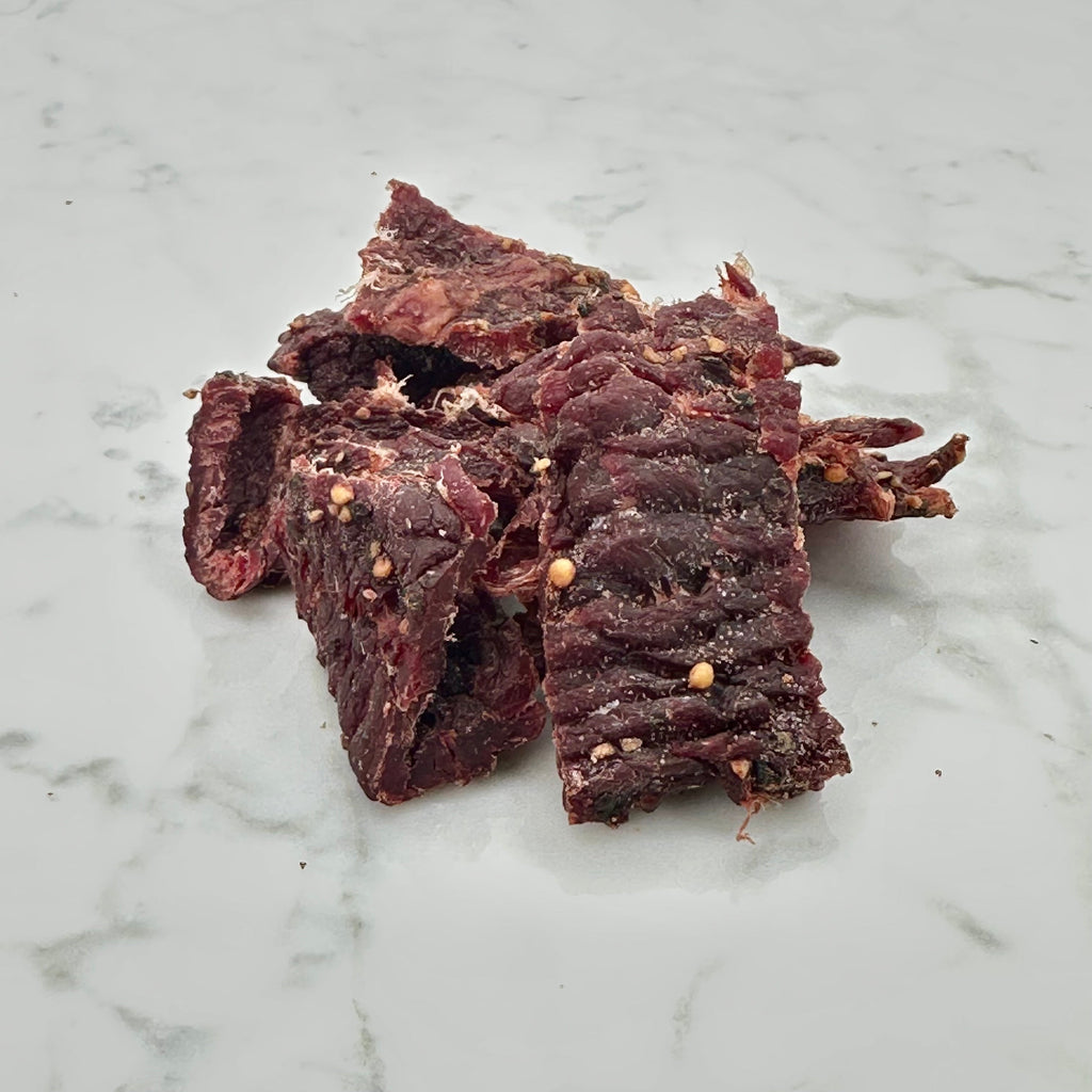 Dark red beef jerky strips, broken pieces in a pile