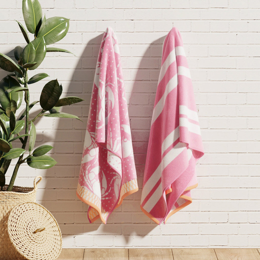 Pink cotton velour towels hanging on a wall, with striped and turtle designs
