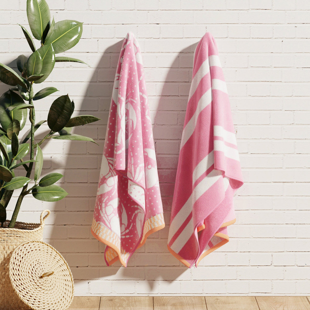 Pink cotton velour towels hanging on a wall, with striped and turtle designs