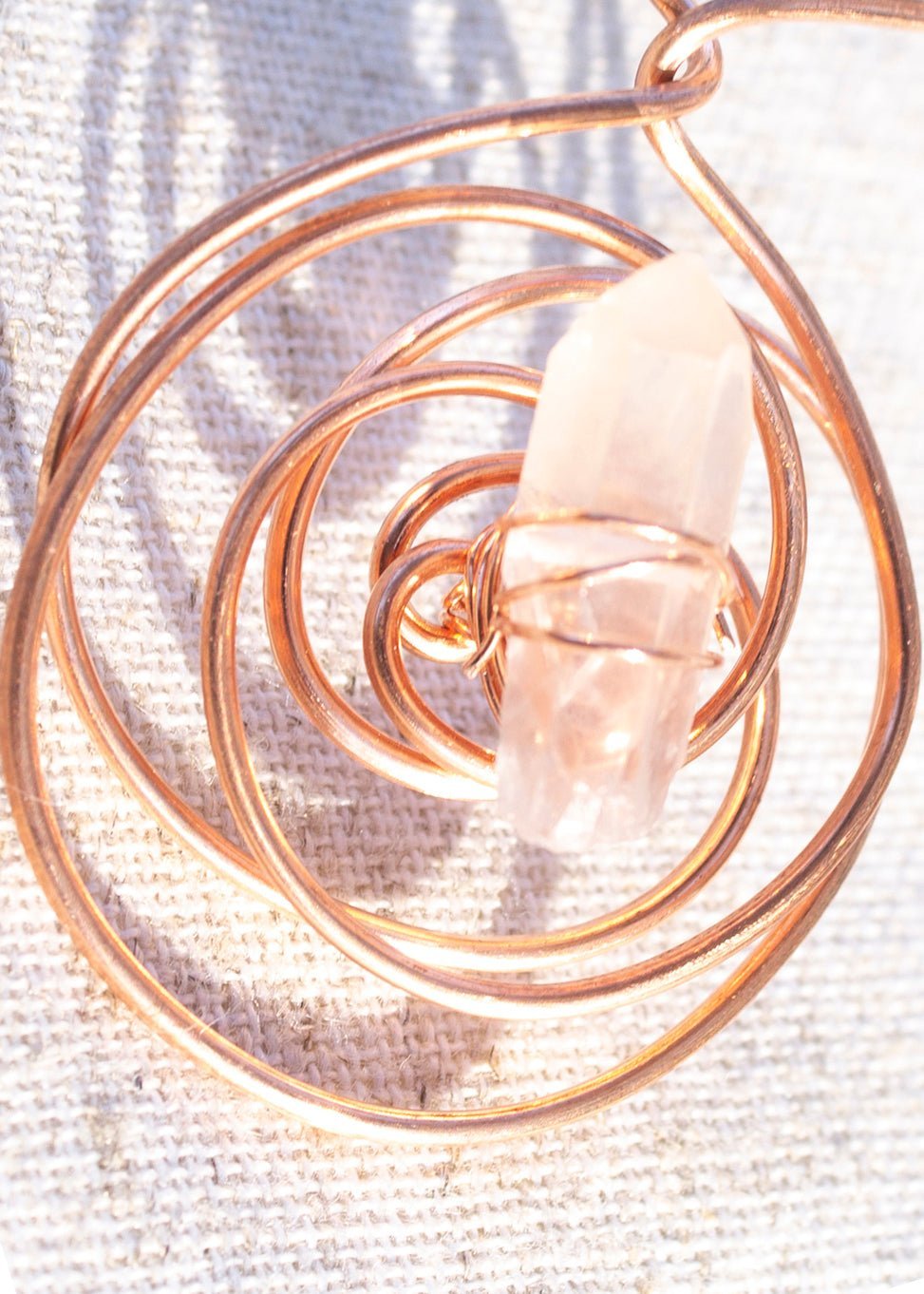 Juti protective necklace close-up showing a clear pink stone wrapped in spiral wire