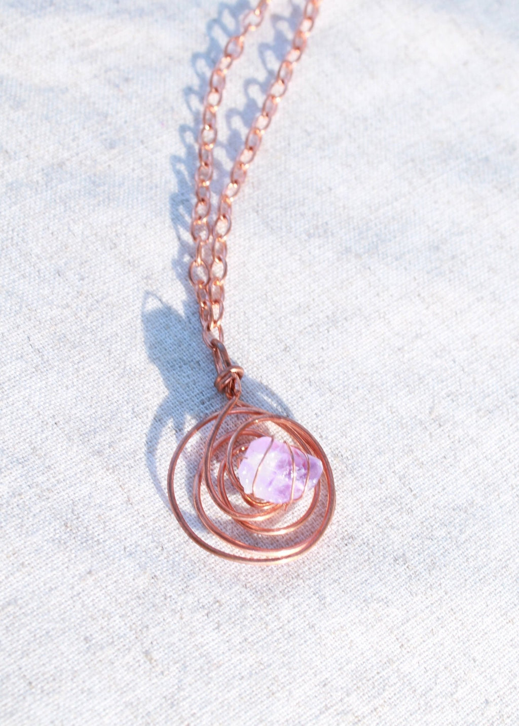 Juti protective necklace with a pale pink stone set in a spiral wire pendant