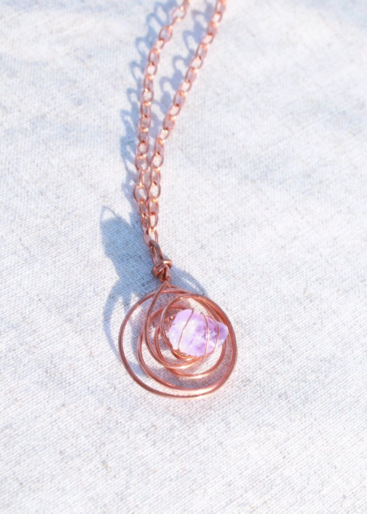Juti protective necklace with a pale pink stone set in a spiral wire pendant