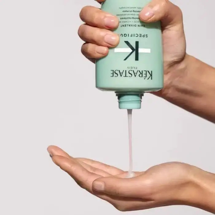 Hand dispensing mint green shampoo from bottle onto palm