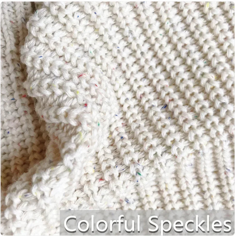 Kids' cotton pullover sweater fabric close-up, white knit with colorful speckles.