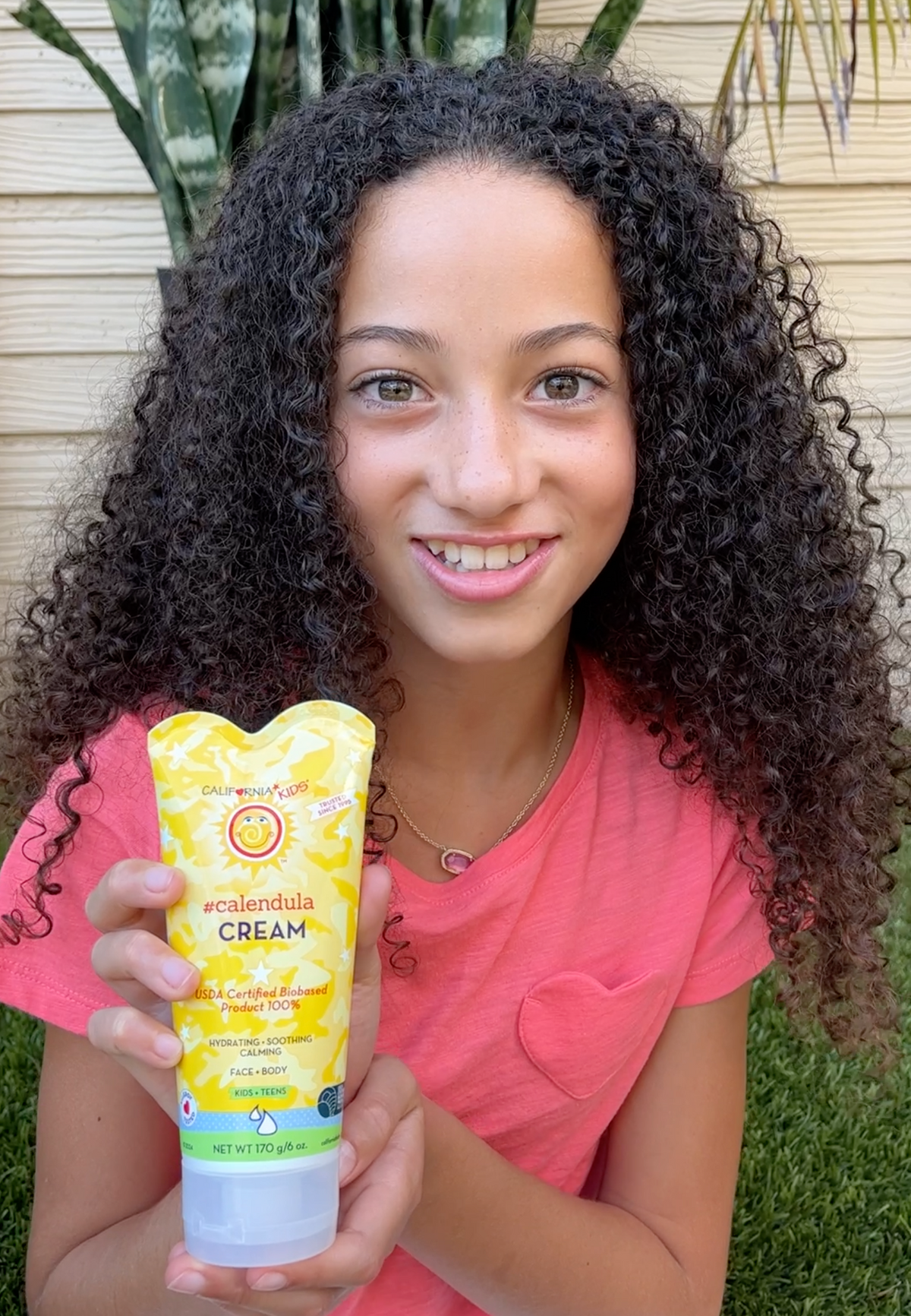 Calendula cream tube held by a person, yellow label and light-blue cap