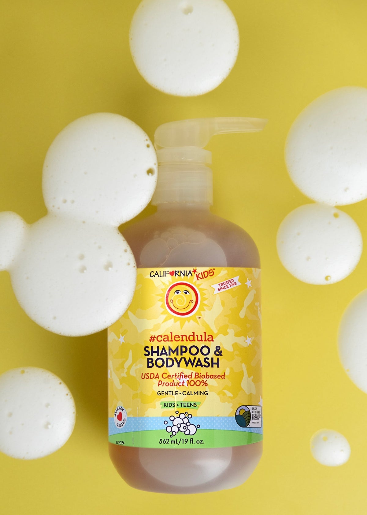 Kids Calendula shampoo & body wash bottle with yellow label, surrounded by white bubbles
