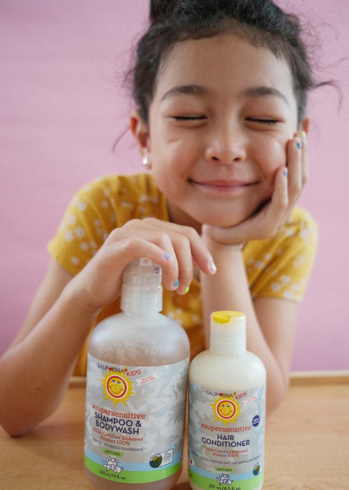 Kids fragrance-free shampoo and conditioner bottles held by child, front-label view
