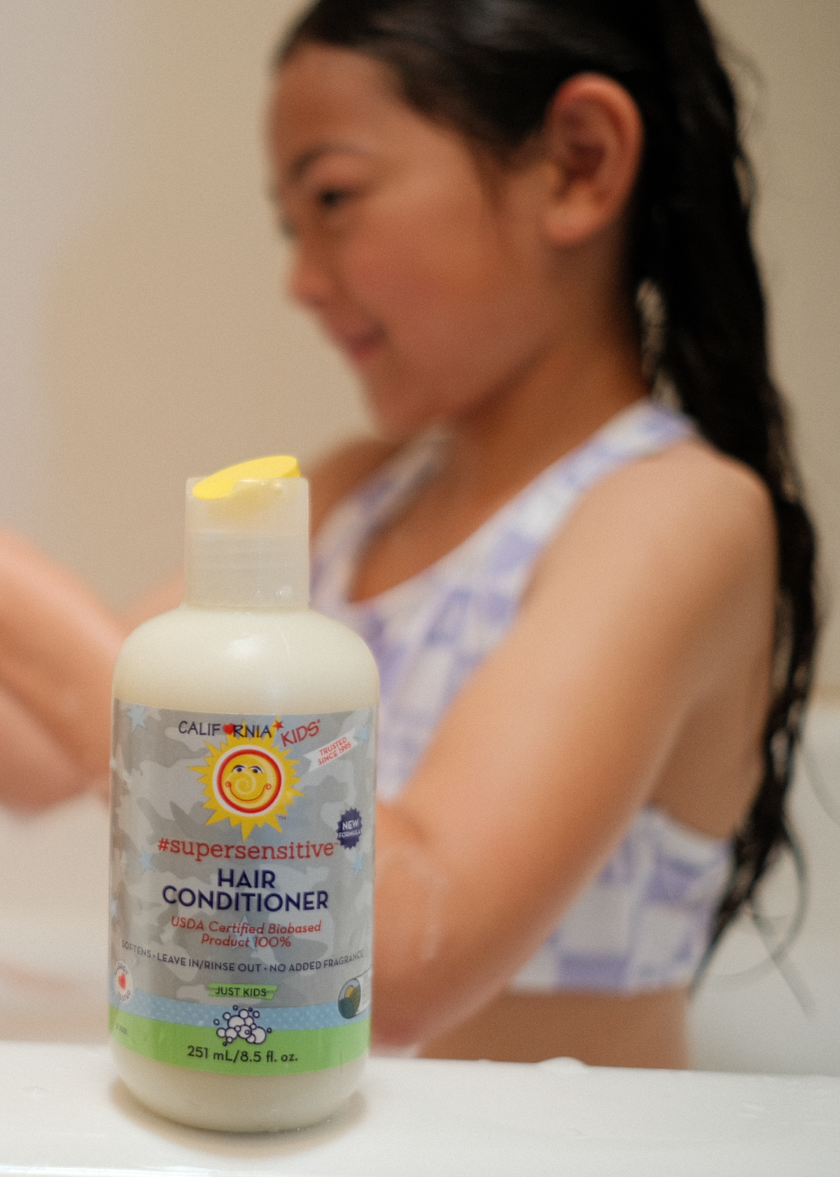 Kids super-sensitive conditioner bottle with pump in front of a child