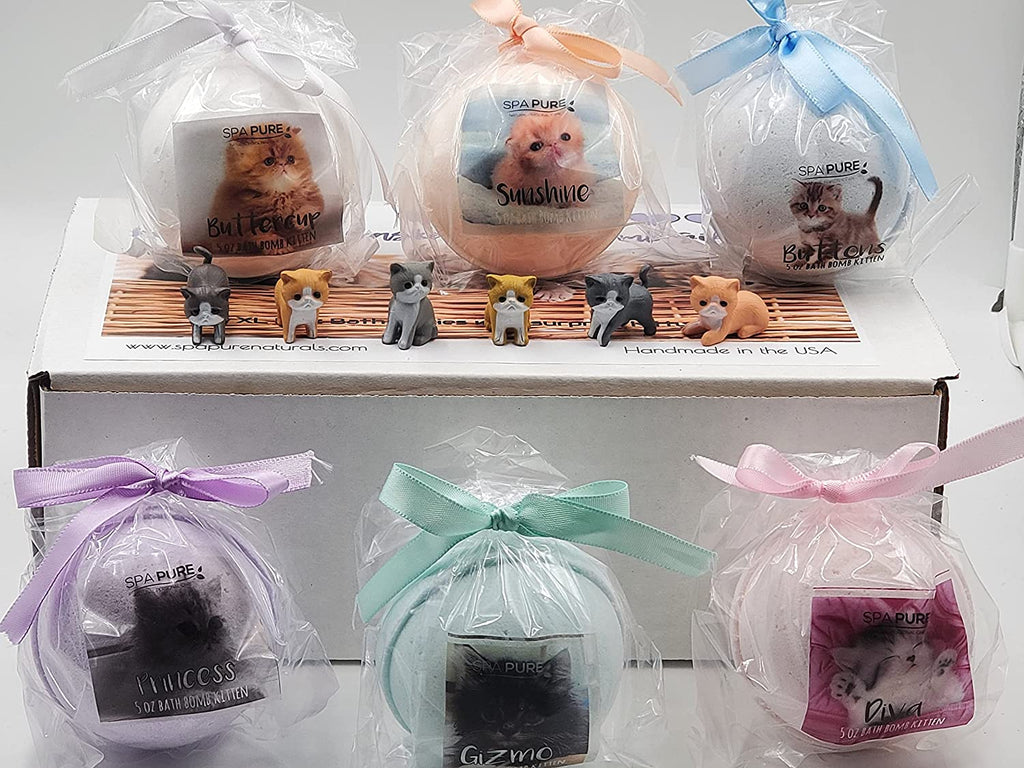 Open gift set with six wrapped bath bombs and small cat figurines on tray