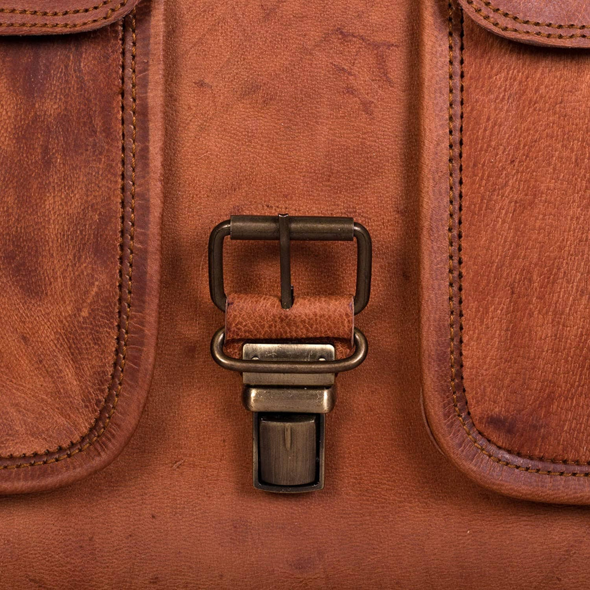 Close-up of leather briefcase strap hardware with metal buckle and rivets in tan.