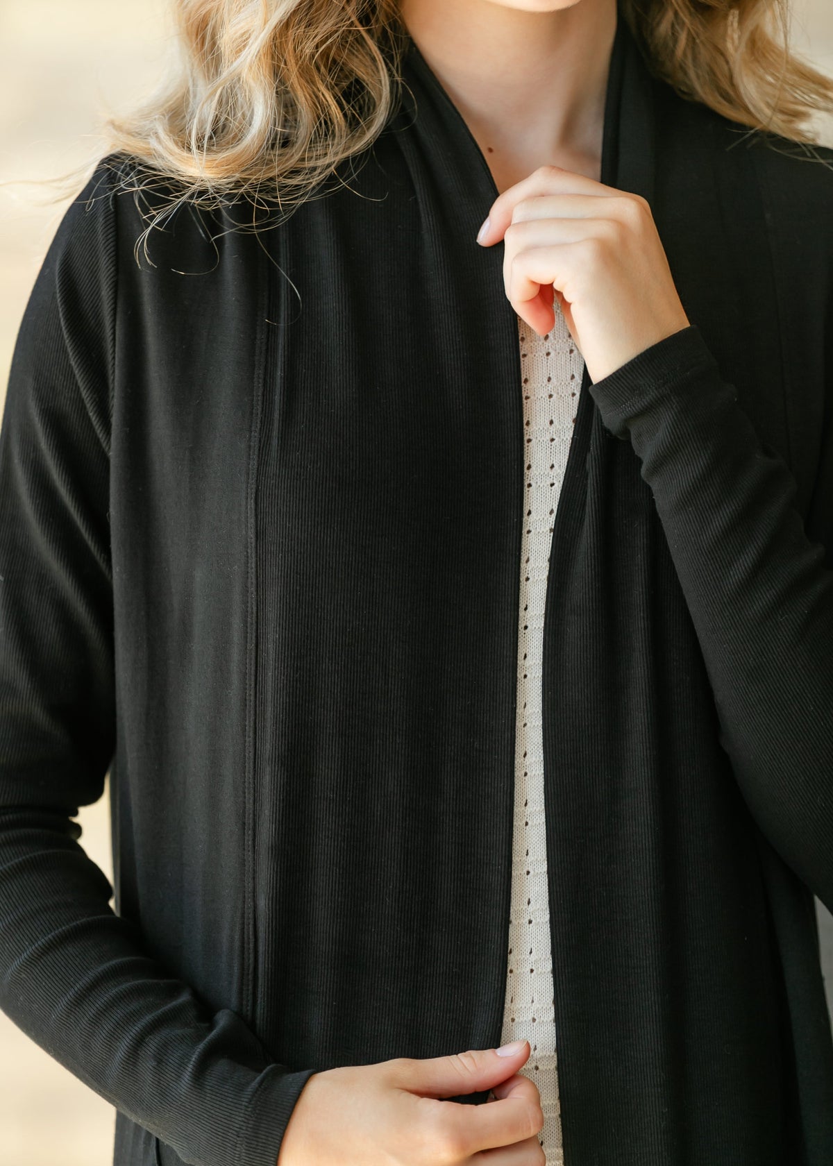 Black open-front cardigan close-up showing draped lapels and long sleeves