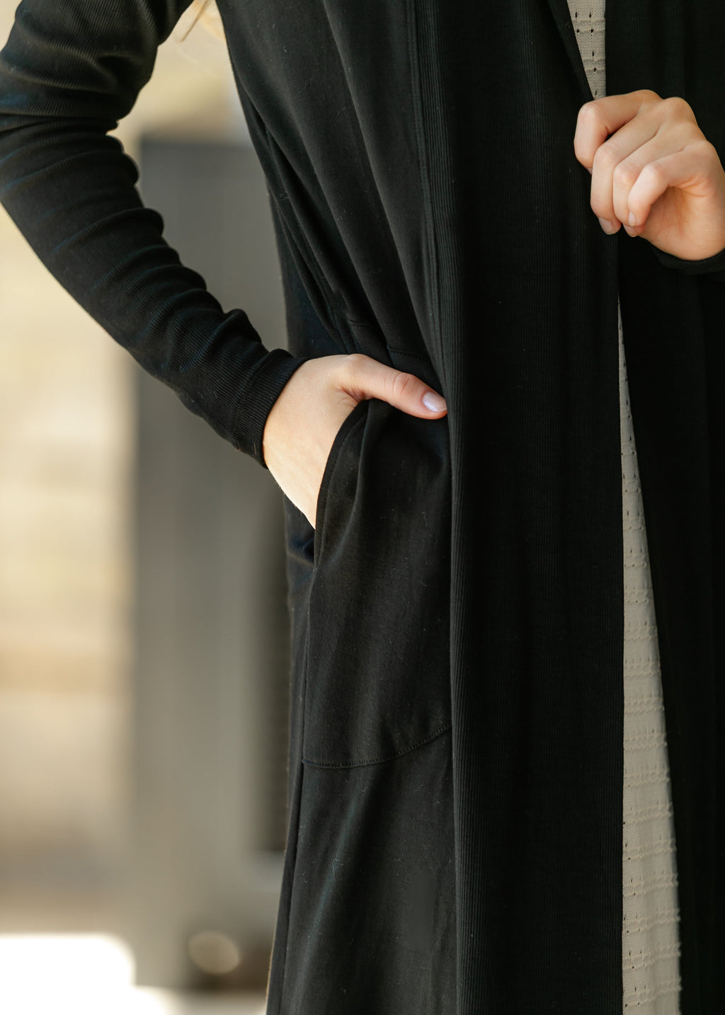 Black open-front cardigan close-up with long sleeves and side pocket detail