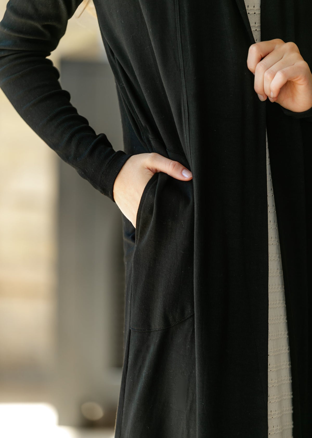 Black open-front cardigan close-up with long sleeves and side pocket detail