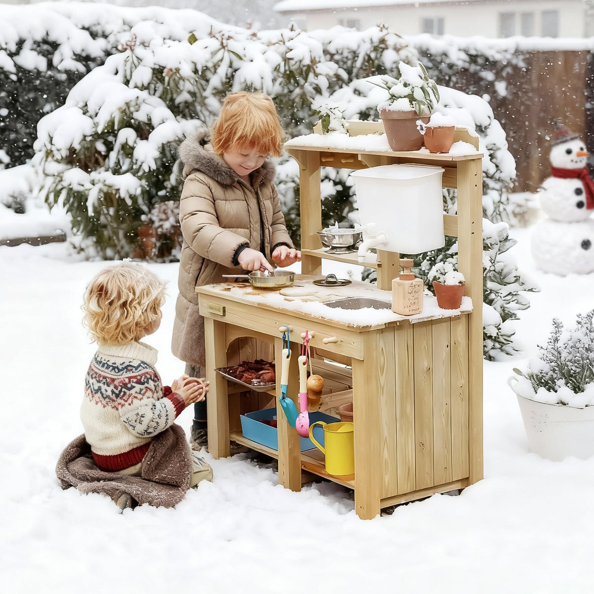 Kids' mud kitchen in light wood with sink and accessories, children playing