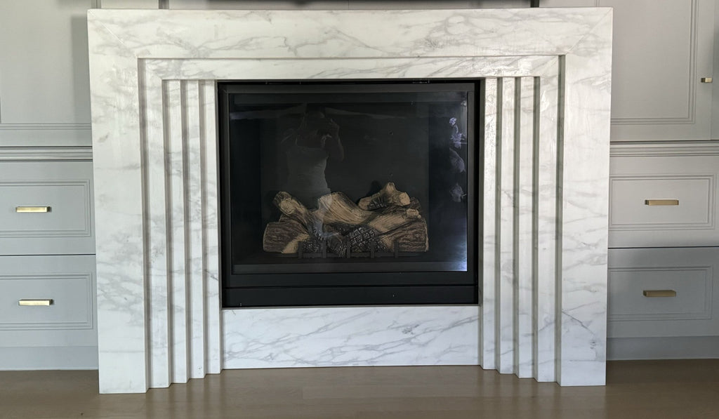 White marble fireplace surround with rectangular glass firebox and burning logs