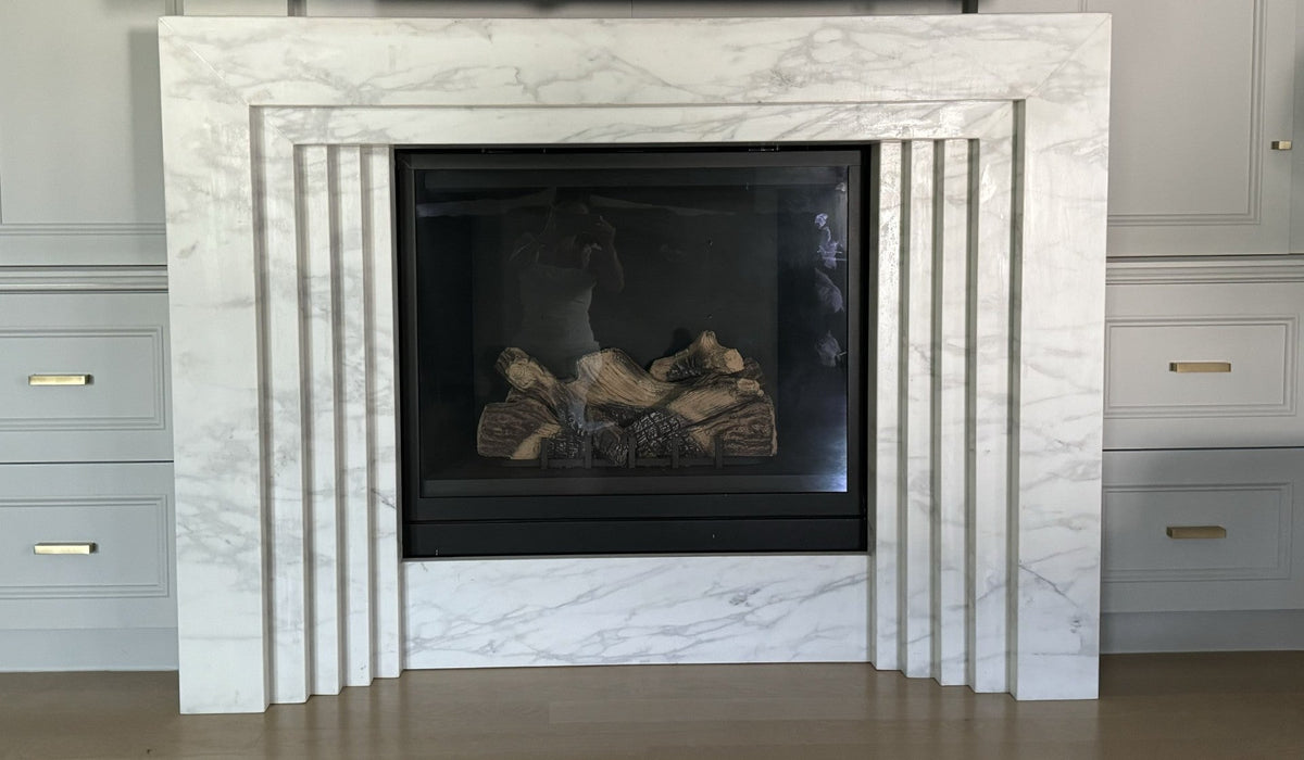 White marble fireplace surround with rectangular glass firebox and burning logs