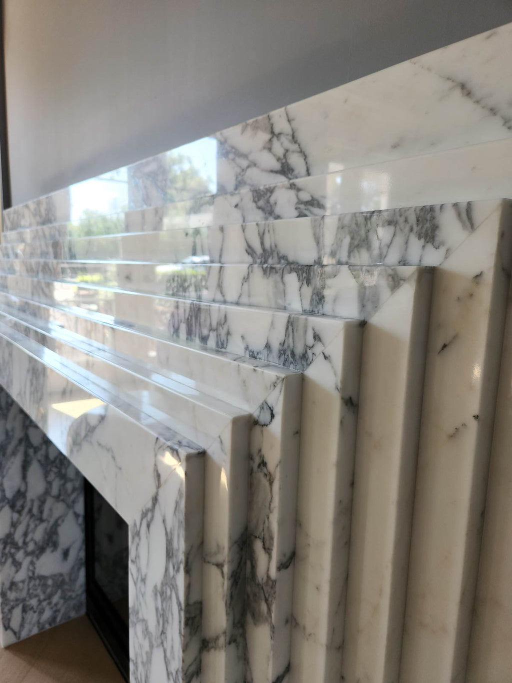 Close-up of marble fireplace surround panels with vertical veining and open hearth view