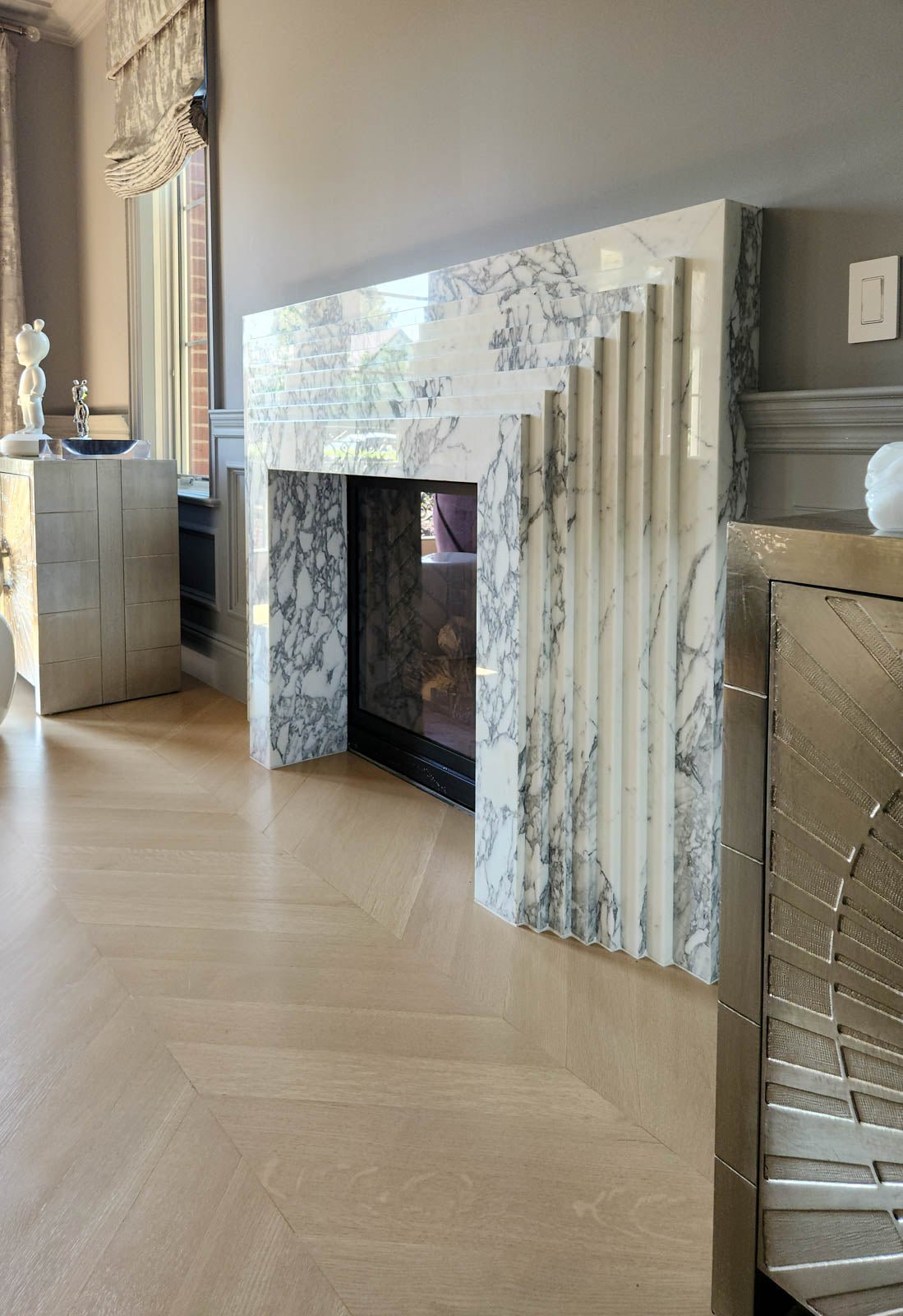 Marble fireplace with open hearth and black insert, shown from an angled side view