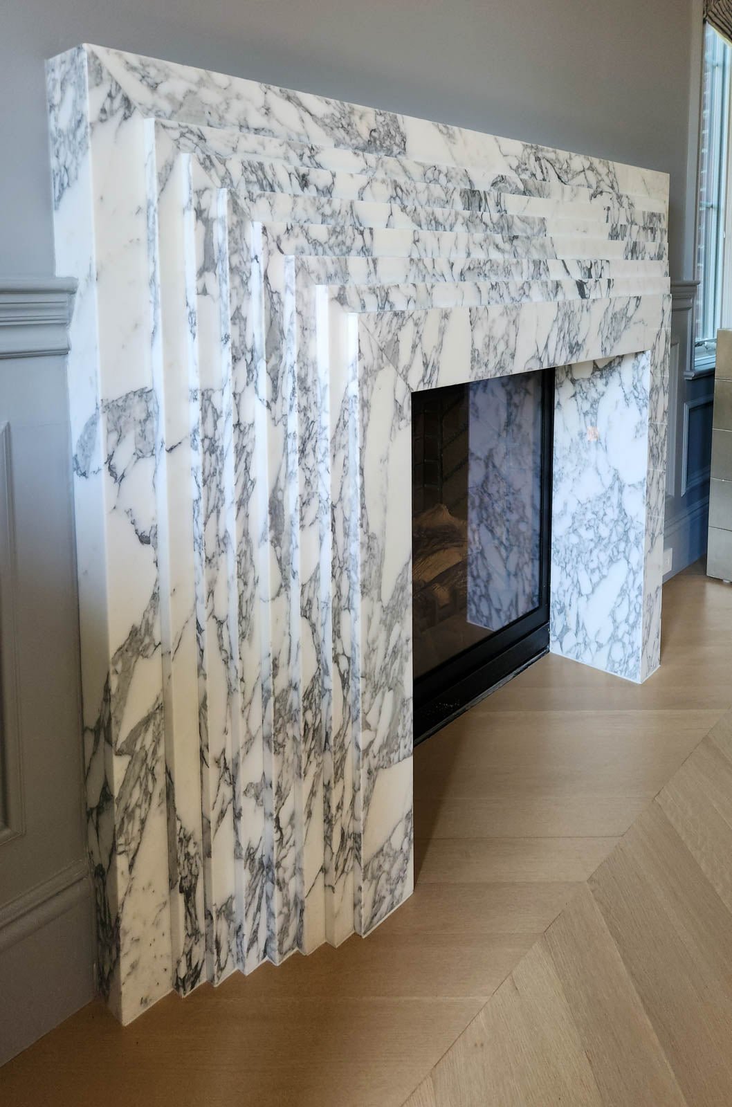 Marble fireplace surround with gray veining and inset firebox opening, no flames visible