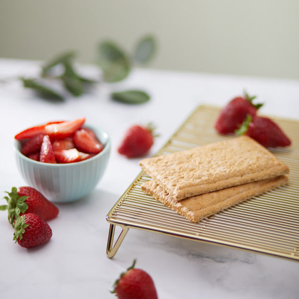 Unfrosted toaster pastries, two tan pastries on cooling rack with strawberries