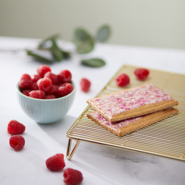 Frosted toaster pastries on rack with raspberries in bowl