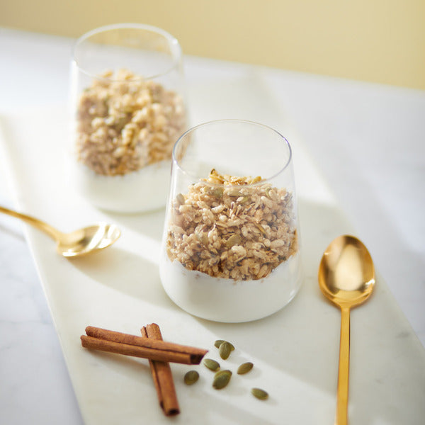 Pumpkin seed + flax granola in clear cups with cinnamon sticks and pumpkin seeds