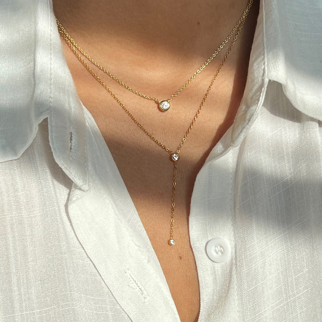 Layered gold chain necklace with round bezel-set diamond pendant