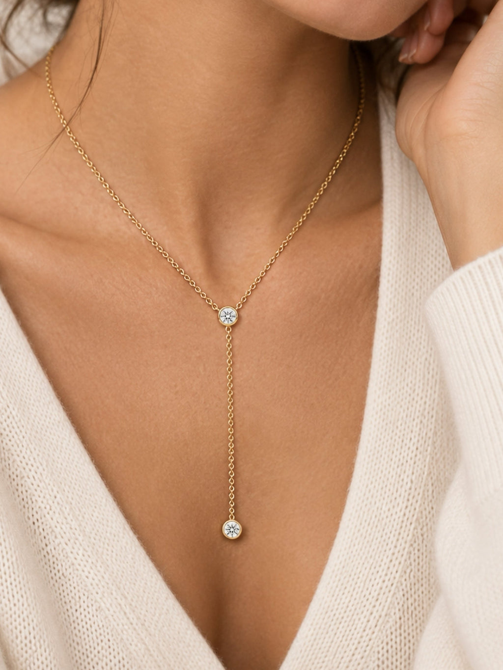 Gold-tone lariat necklace on neckline with round bezel diamond charms