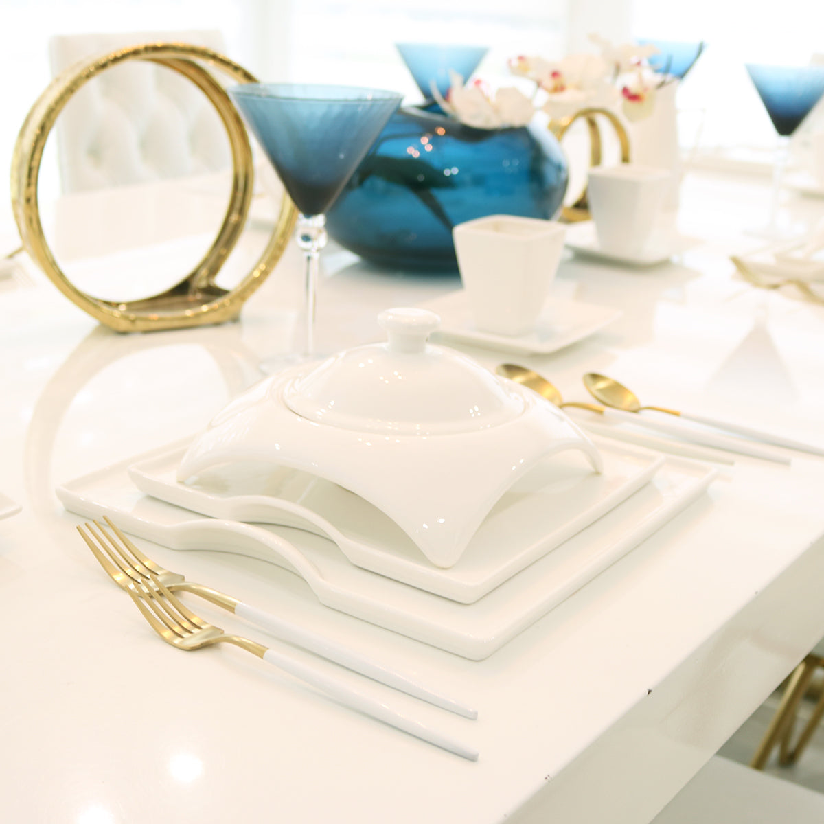 White porcelain square plates with stacked serving pieces and a covered dish