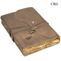 Leather journal with strap closure and metal key on front, dark brown.