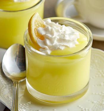 Lemon creme pudding in a glass cup topped with whipped cream and lemon slice