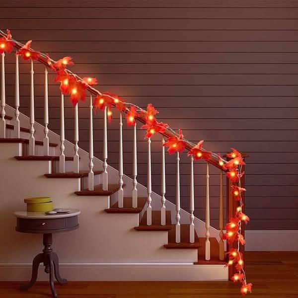 Lighted fall leaf LED string lights along a staircase railing with glowing orange-red leaves